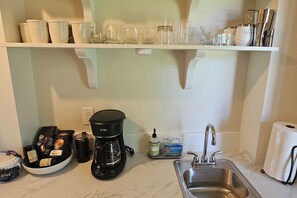A kitchen with a coffee maker, a sink, and various kitchen items on the countertop. - Downtown Driggs base for Yellowstone/Grand Teton (Driggs)