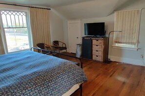 A bedroom with a bed, a dresser, a television, and a window with curtains. - Downtown Driggs base for Yellowstone/Grand Teton (Driggs)