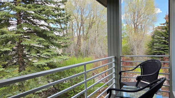 A balcony with a glass table and chairs, overlooking a forested area. - Sleeps 10! Updated Townhome Off Ski Hill Rd (Driggs)