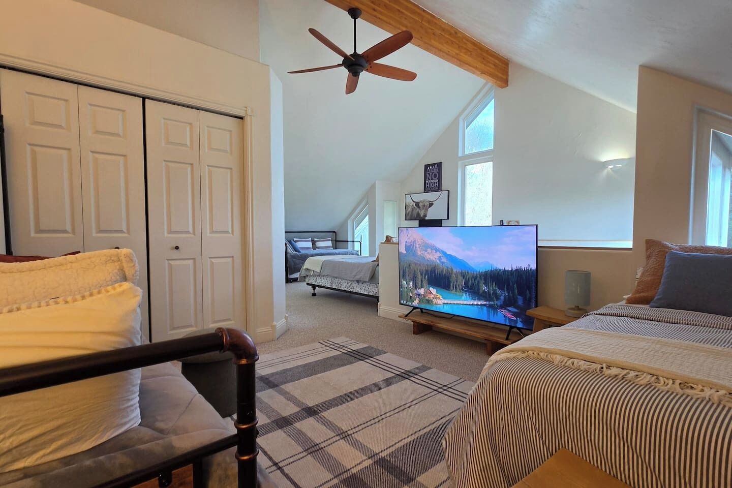 Un dormitorio con cama, televisión, ventilador de techo y vistas a un paisaje montañoso.