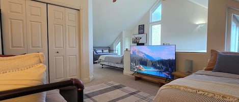 Un dormitorio con cama, televisión, ventilador de techo y vistas a un paisaje montañoso.