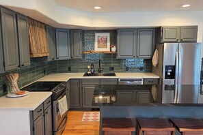 A modern kitchen with grey cabinets, a stainless steel refrigerator, and a dishwasher. - Sleeps 10! Updated Townhome Off Ski Hill Rd (Driggs)