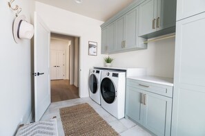 A laundry room with a washing machine, a drying rack, and a small potted plant. - White Pine Lodge in Teton Valley (Driggs)