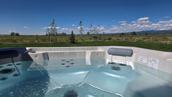 A hot tub with a clear view of a grassy field and mountains in the background. - White Pine Lodge in Teton Valley (Driggs)