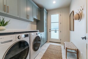 A laundry room with two LG ThinQ washing machines, a potted plant, a bench, and a door leading outside. - White Pine Lodge in Teton Valley (Driggs)