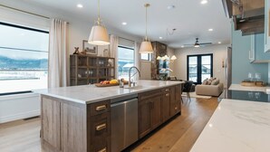 Een moderne keuken met een groot eiland, houten kastjes en hanglampen.