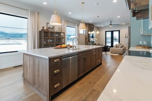 A modern kitchen with a large island, wooden cabinets, and pendant lighting. - White Pine Lodge in Teton Valley (Driggs)