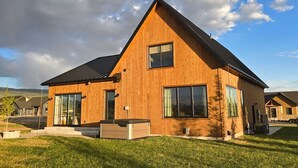 Een modern houten huis met twee verdiepingen, grote ramen en een schuin dak.
