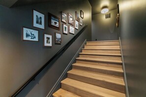 A staircase with wooden steps and a handrail, leading to a landing with a light fixture and framed pictures on the wall. - White Pine Lodge in Teton Valley (Driggs)