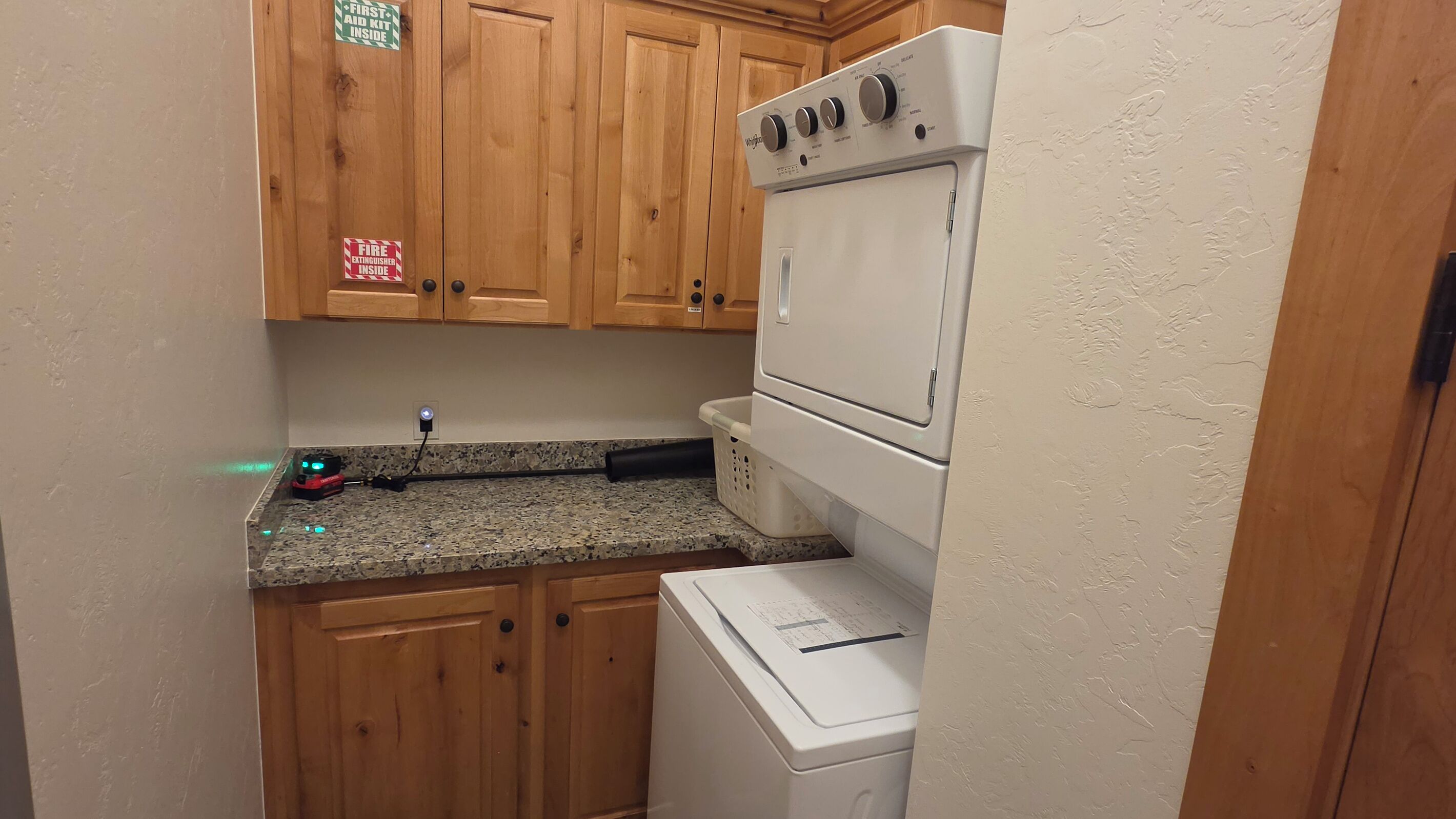 A compact kitchen with wooden cabinets, a washing machine, and a countertop with a power strip.
