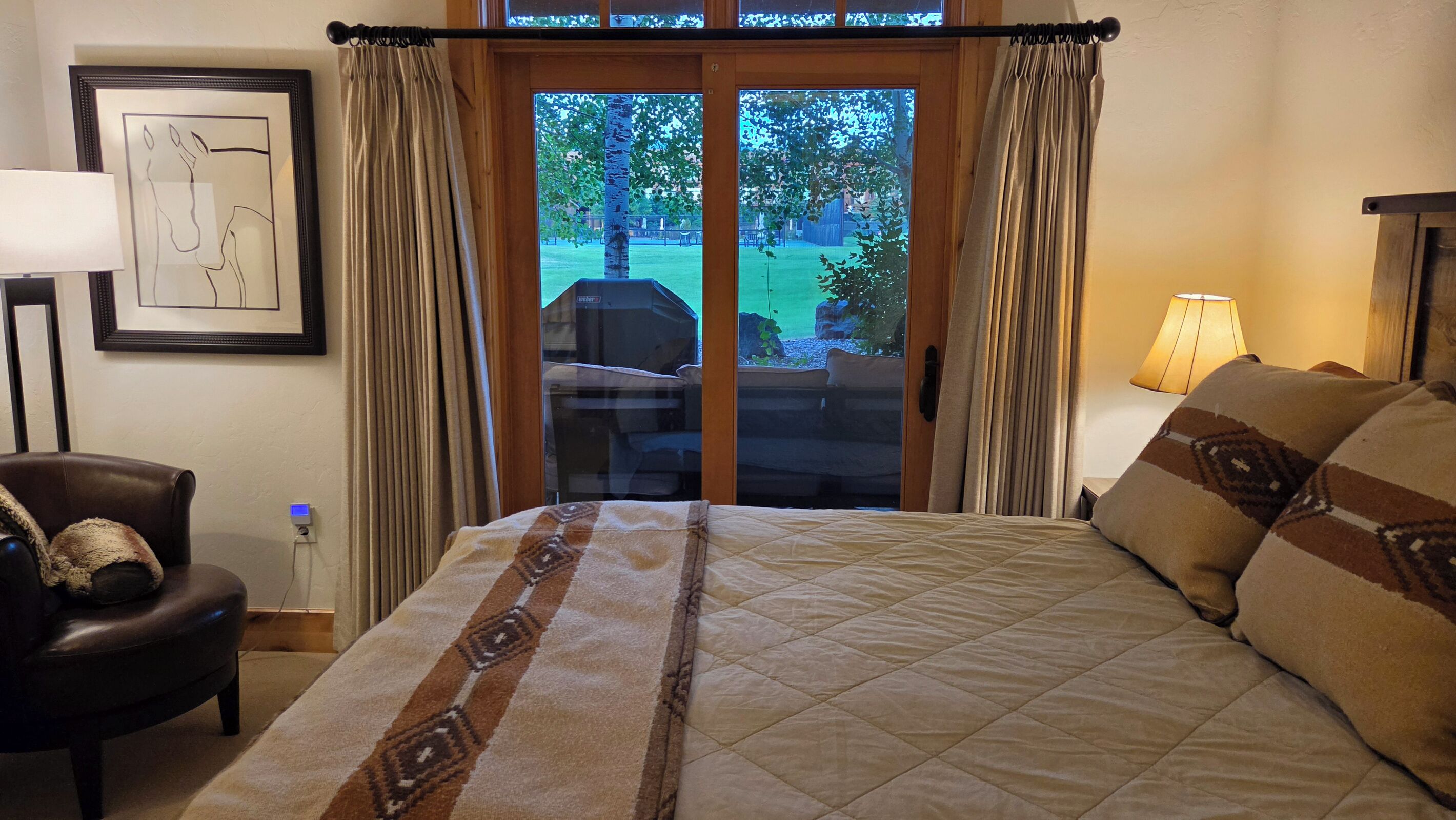 Une chambre d’hôtel comprenant un lit, une chaise, une lampe et une porte donnant sur un espace extérieur.