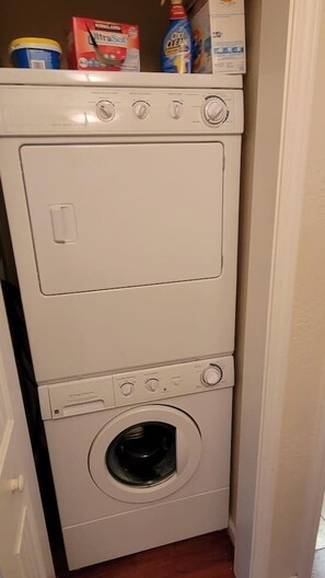 Un appareil combiné lave-linge et sèche-linge, de type « empilable », avec des compartiments à lessive situés sur le dessus.