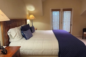 A bedroom with a bed, pillows, a nightstand, a lamp, and a chair. - Teton Creek Getaway with Hot Tub (Driggs)