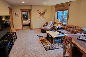 A cozy living room with a fireplace, comfortable seating, and a view of the outdoors through a window. - It's Always "Peak" Season in the Tetons (Tetonia)