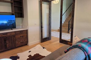 A living room with a television, wooden cabinets, a cowhide rug, and a staircase leading to another level. - Teton Reserve Royal Elk Lodge (Victor)