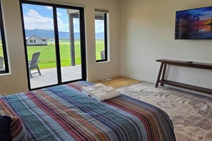 A bedroom with a bed, a large window, and a painting on the wall. - Teton Reserve Royal Elk Lodge (Victor)