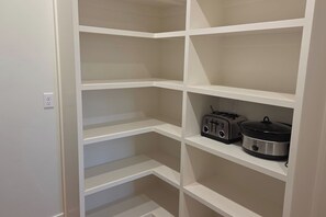 A white shelving unit with multiple compartments, some containing kitchen appliances like a toaster and a slow cooker. - Teton Reserve Royal Elk Lodge (Victor)