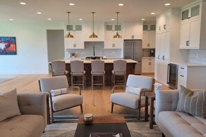 A modern kitchen with white cabinets, a central island with chairs, and pendant lighting. - Teton Reserve Royal Elk Lodge (Victor)