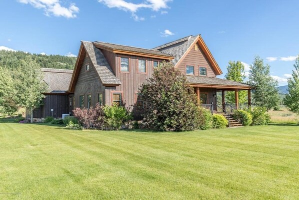 A two-story wooden house with a large front lawn and a covered porch.