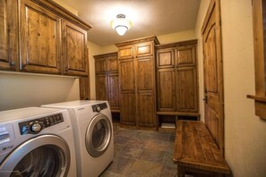 Un cuarto de lavado con gabinetes de madera, una lavadora y un banco.