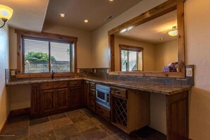 Una cocina con armarios de madera, horno empotrado, enfriador de vino y un espejo grande.