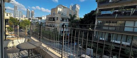 A balcony with a patterned floor, a metal railing, and a table with chairs.