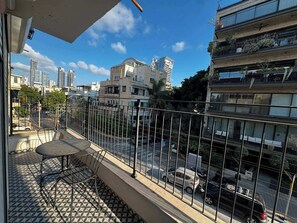 A balcony with a patterned floor, a metal railing, and a table with chairs. - Modern 2BR with Sunny Balcony by HolyGuest (Tel Aviv-Yafo)