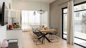 Une cuisine moderne avec un coin repas, une grande fenêtre avec des rideaux et une vue sur l’extérieur.