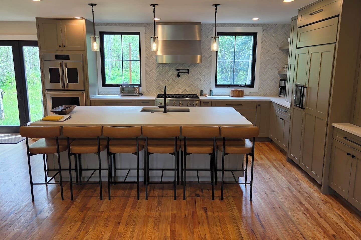 A modern kitchen with a large island, bar stools, and built-in appliances.
