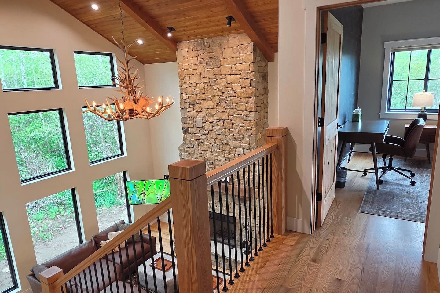 Un intérieur à plusieurs niveaux, avec un mur en pierre, une rambarde en bois et un lustre.