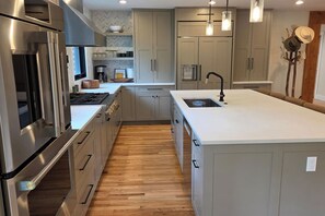 A modern kitchen with stainless steel appliances, a large island, and light wood flooring.