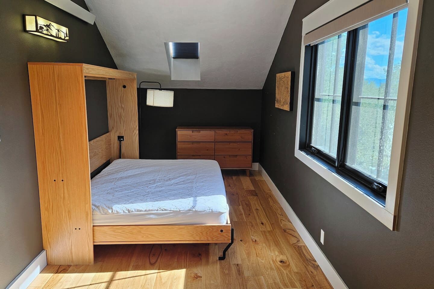 A bedroom with a bunk bed, a dresser, a window with a view, and a ceiling light.