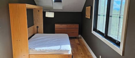 A bedroom with a bunk bed, a dresser, a window with a view, and a ceiling light.