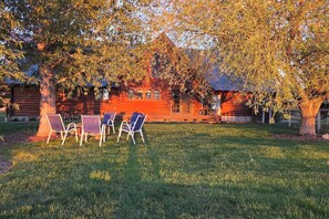 A wooden cabin with a grassy lawn and a tree. - Wild Cat Lodge with Fenced Yard and Teton View (Driggs)