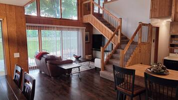 A spacious living area with a wooden staircase, a dining table, and a comfortable seating arrangement.