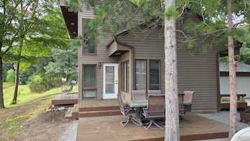 A two-story house with a deck, outdoor seating, and a garage.