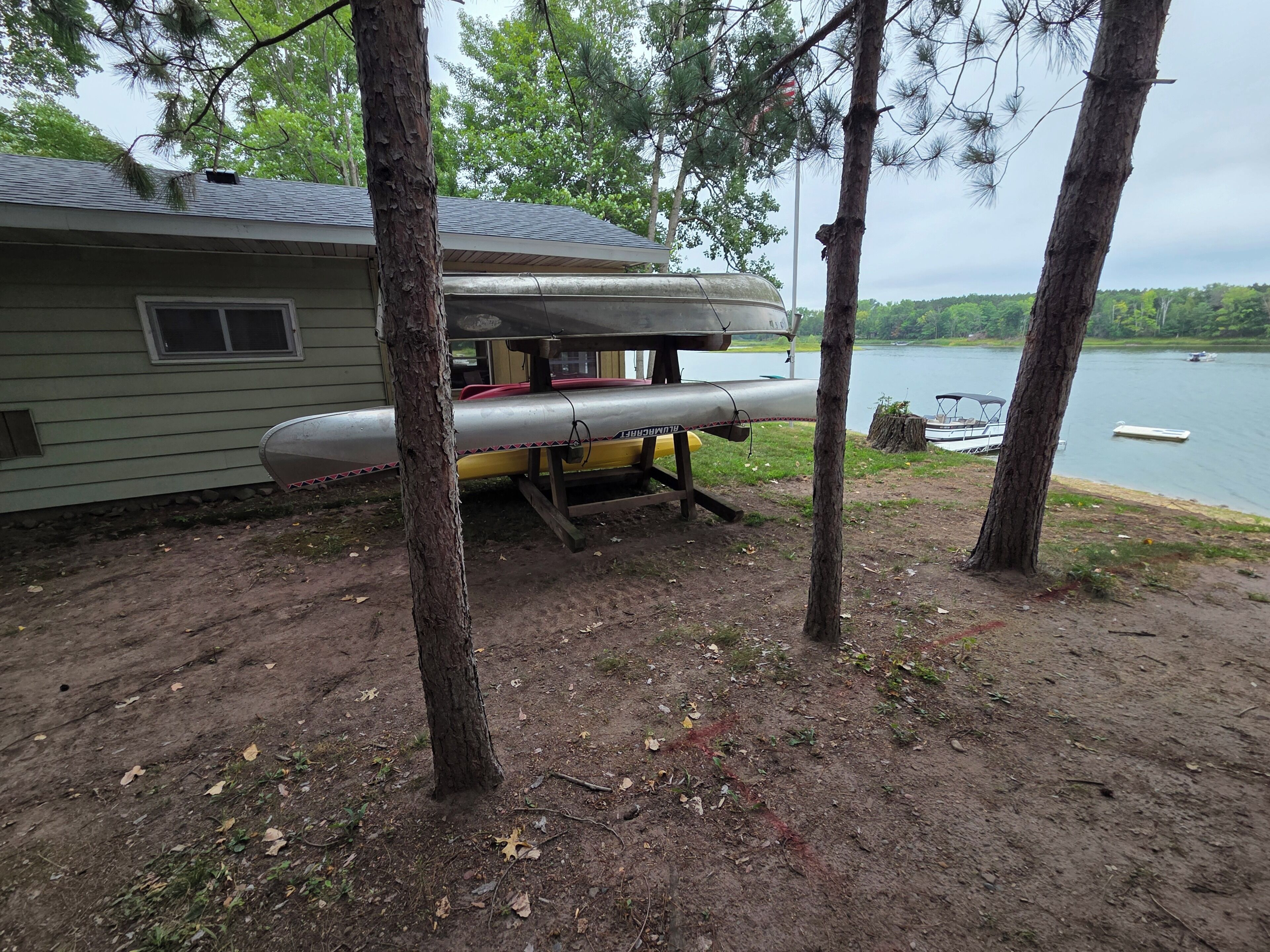 A lakeside cabin with a canoe and kayak docked outside, surrounded by trees.