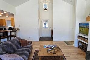 A spacious living area with a sofa, coffee table, and a television on a stand. - Teton Creek Resort Home (Driggs)