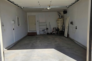 A garage with a concrete floor, a door, and various tools and equipment. - Teton Creek Resort Home (Driggs)