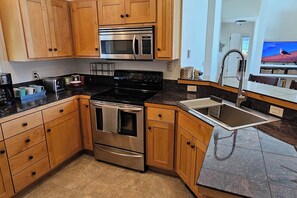 A kitchen with wooden cabinets, a stainless steel stove, a microwave, and a sink. - Teton Creek Resort Home (Driggs)