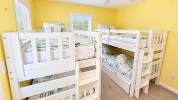 A room with bunk beds, a ceiling fan, and two windows with blinds.