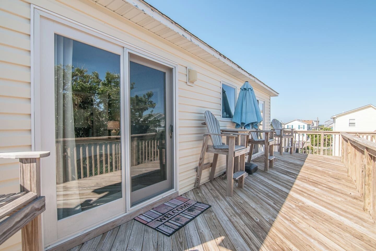 A deck with a sliding glass door, outdoor seating, and a welcome mat.