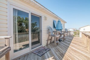 A deck with a sliding glass door, outdoor seating, and a welcome mat.