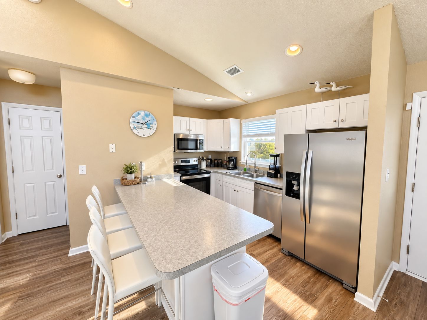 A modern kitchen with white cabinets, stainless steel appliances, and a central island.