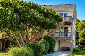 A multi-story residential building with a wooden staircase, a balcony, and a well-maintained garden.