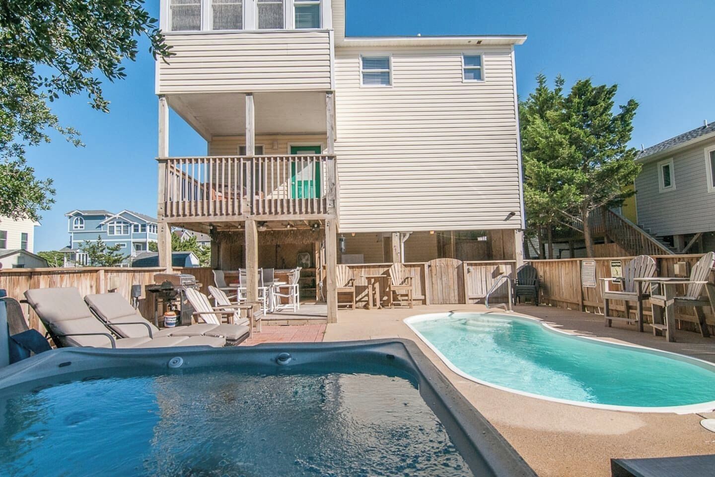 A two-story house with a backyard pool, outdoor furniture, and a wooden deck.