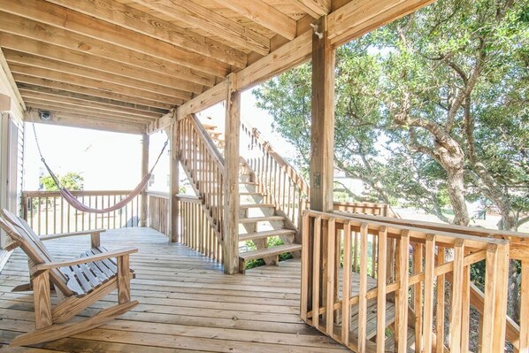 A wooden deck with a hammock, wooden stairs, and a railing.