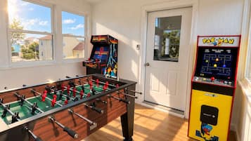 A room with a foosball table, a Pac-Man arcade machine, and a door with a window.