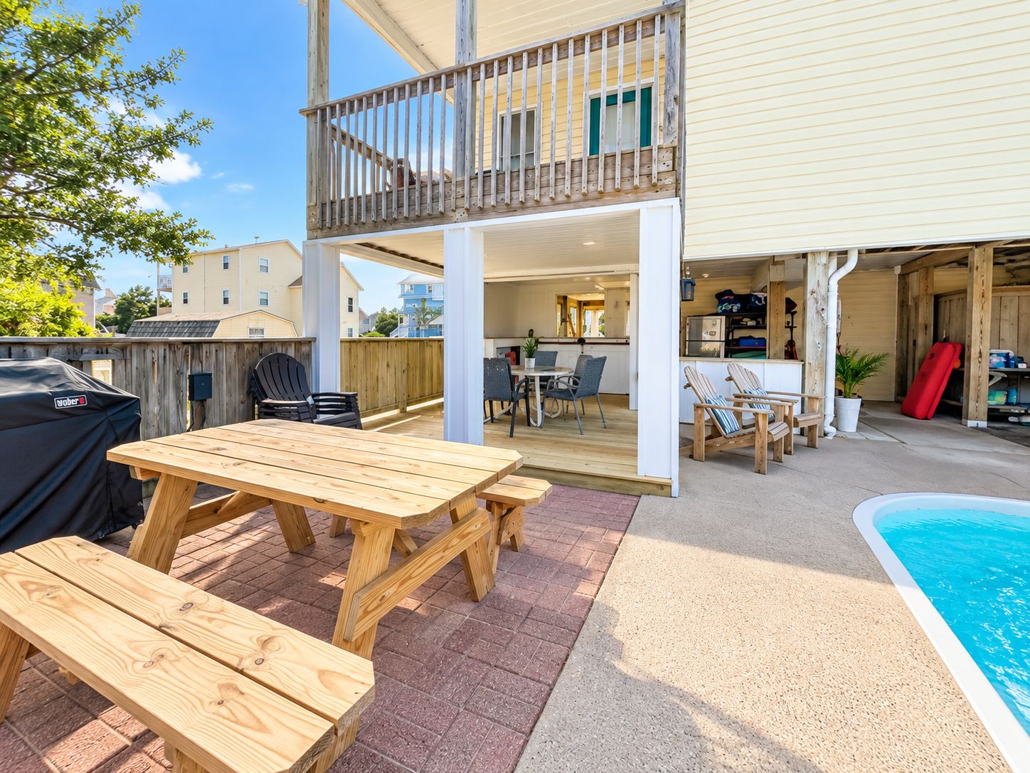 A two-story house with a covered patio, a pool, and a barbecue grill.