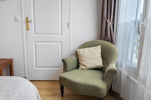 A room with a green upholstered armchair, a white door, and a window with curtains. - Bed and Breakfast 'Chambre 2' with Shared Terrace, Shared Garden and Wi-Fi (Merville-Franceville-Plage)